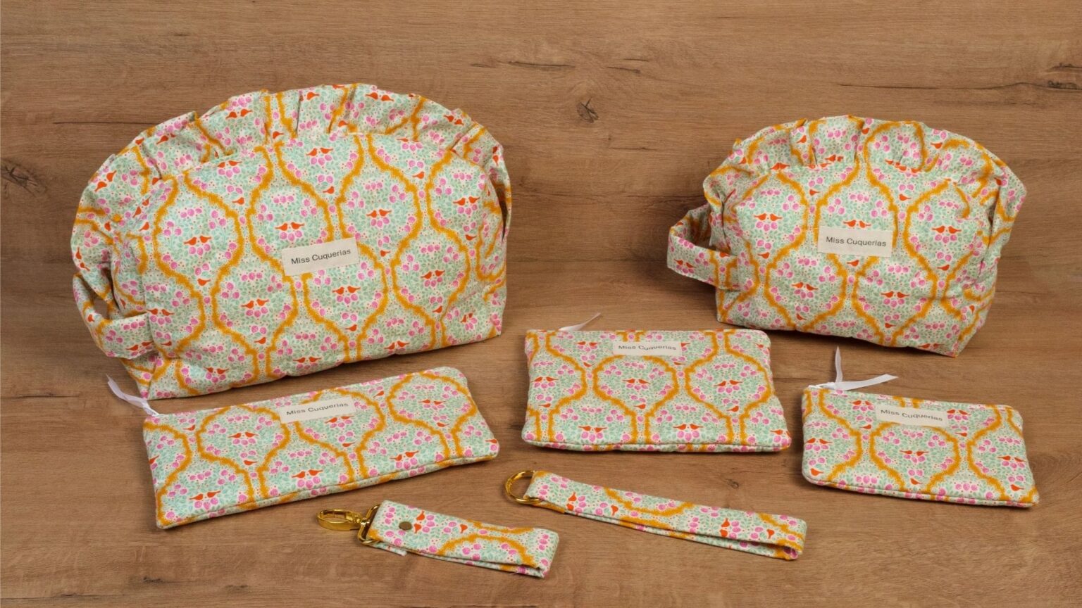 Neceseres, estuche, funda de libro y llaveros con el estampado Anne sobre una mesa de madera